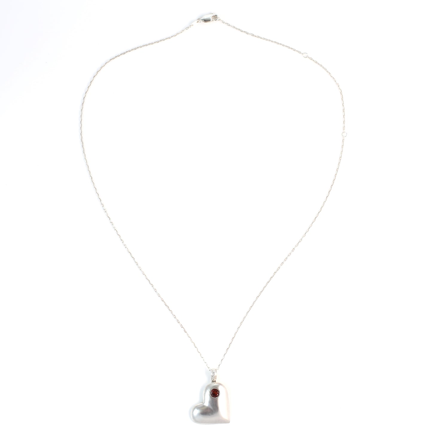 Handmade sterling silver offset heart pendant necklace with faceted natural red garnet gemstone. One of a kind by Cara Carter Jewelry