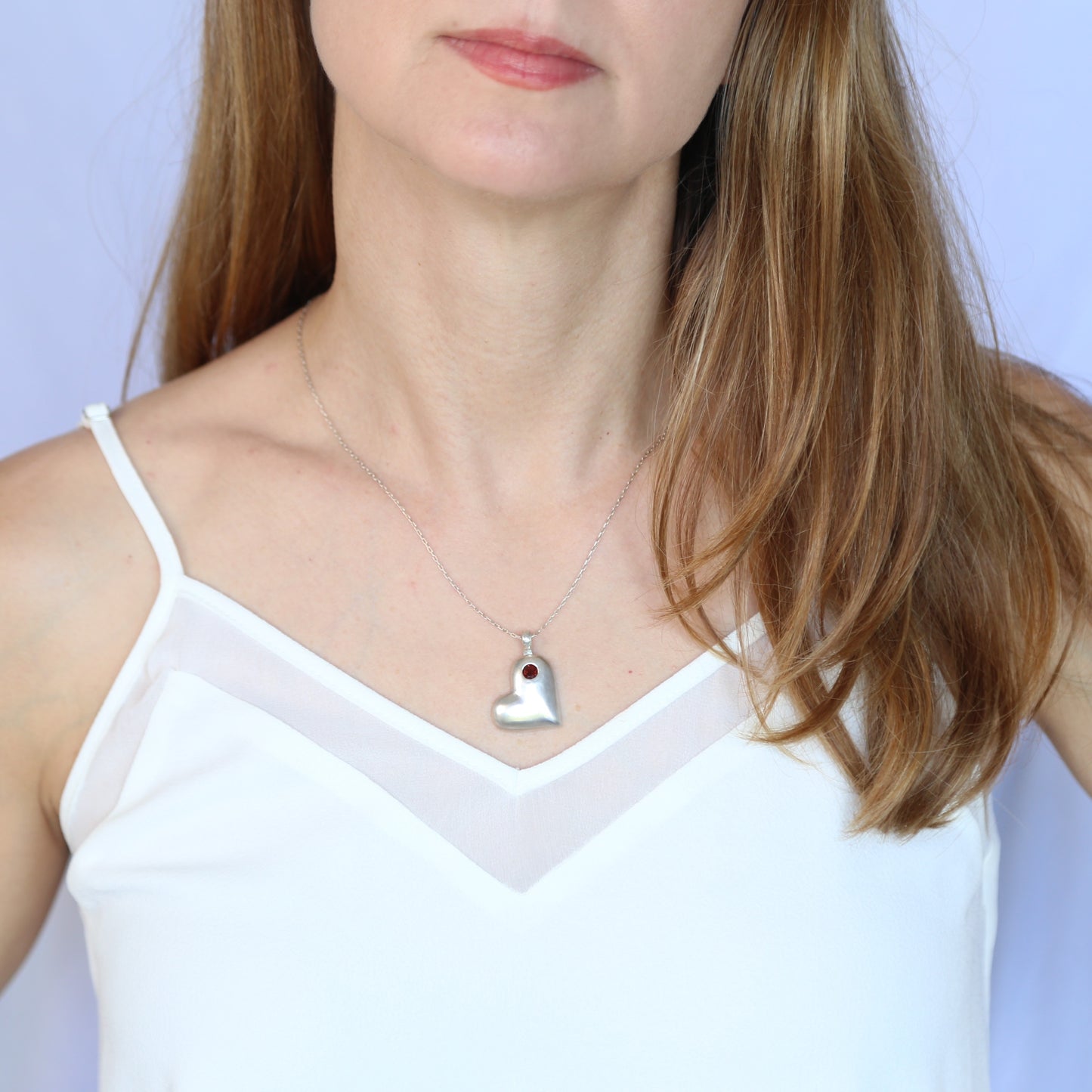 Handmade sterling silver offset heart pendant necklace with faceted natural red garnet gemstone. One of a kind by Cara Carter Jewelry