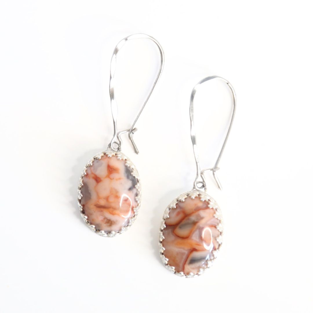 Lace Agate Oval Gemstones in Pink and Gray, set in a patterned sterling silver bezel with long texturized kidney ear wires. Handmade by Cara Carter Jewelry