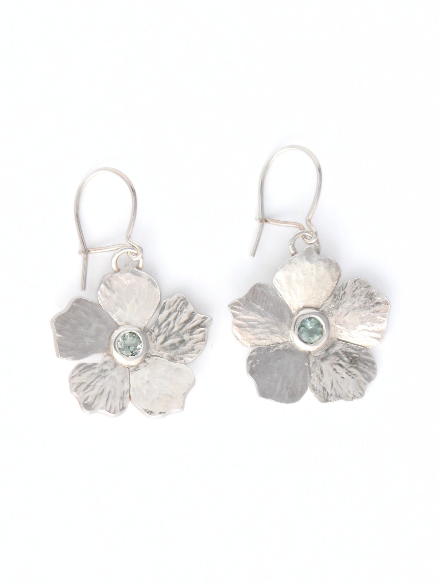 Silver flower-shaped earrings with a central light blue tourmaline gemstone on a white background