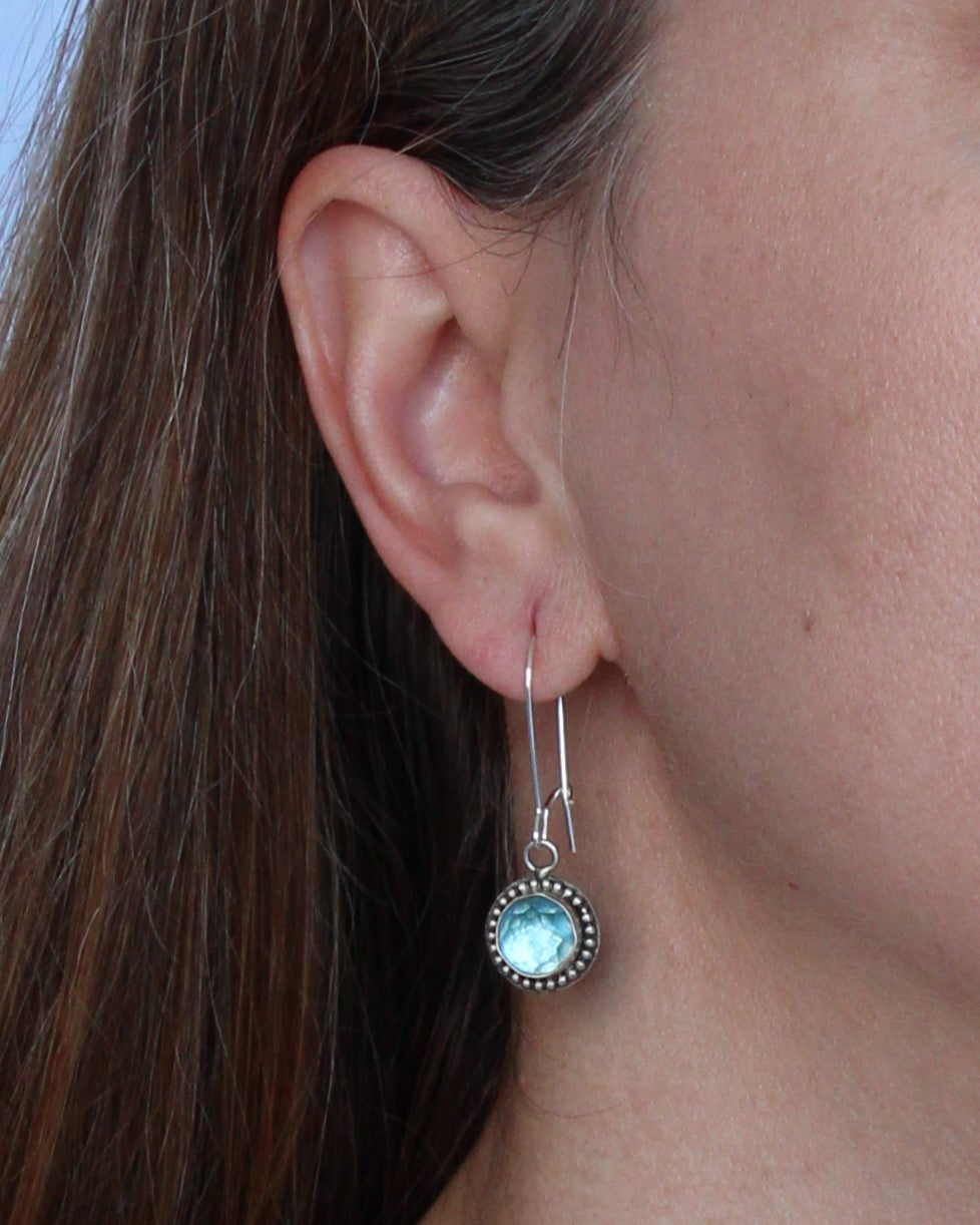 Handmade earrings featuring Swiss Blue Topaz faceted round gemstones set in sterling silver with beaded surround and long kidney hook earwires. By Cara Carter Jewelry