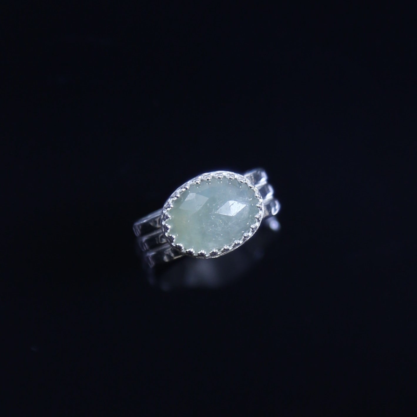 Natural Faceted Light Green Oval Sapphire Set in Sterling Silver with a triple band and patterned bezel. One of a kind and handmade by Cara Carter Jewelry