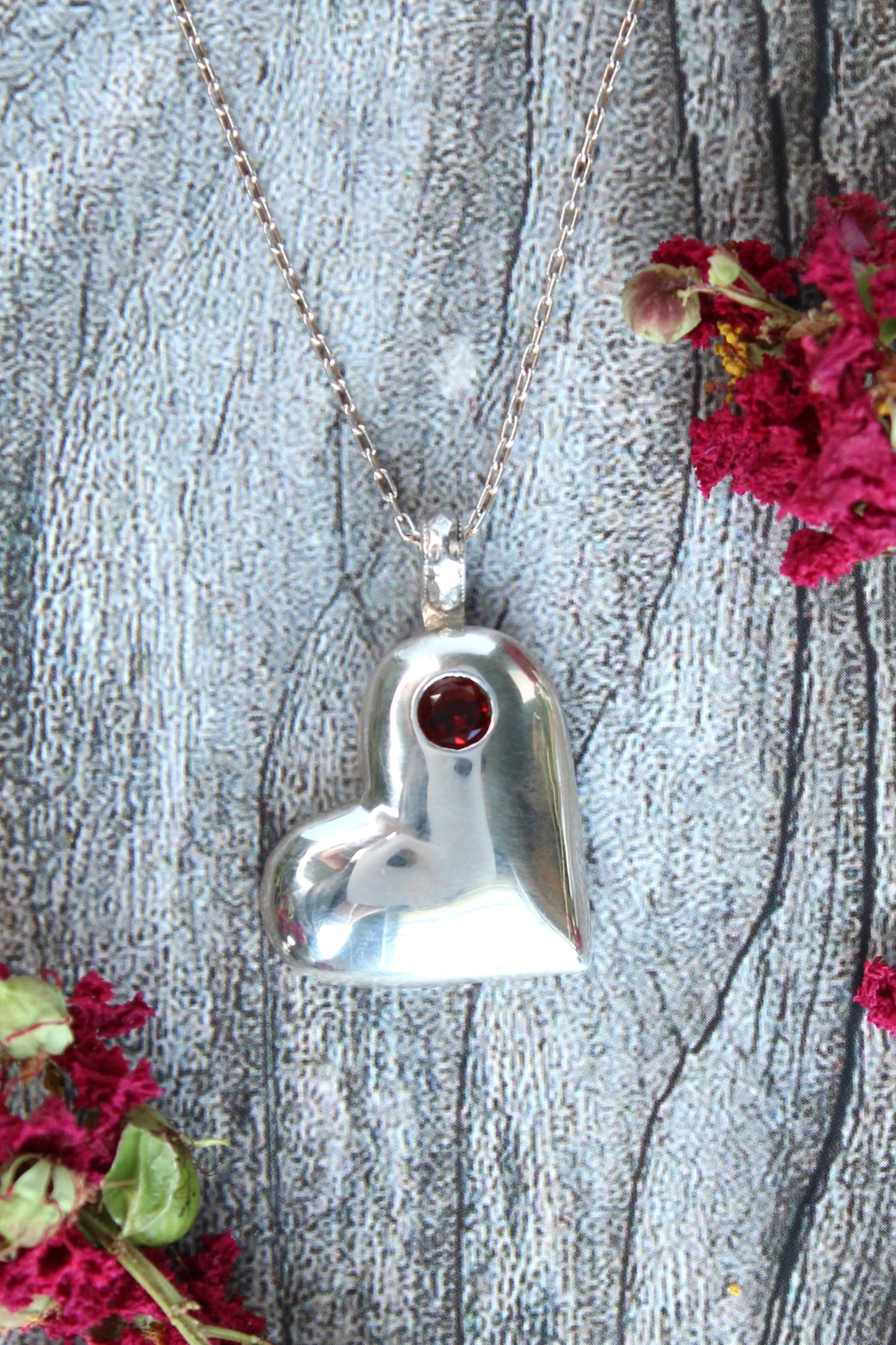 Handmade sterling silver offset heart pendant necklace with faceted natural red garnet gemstone. One of a kind by Cara Carter Jewelry