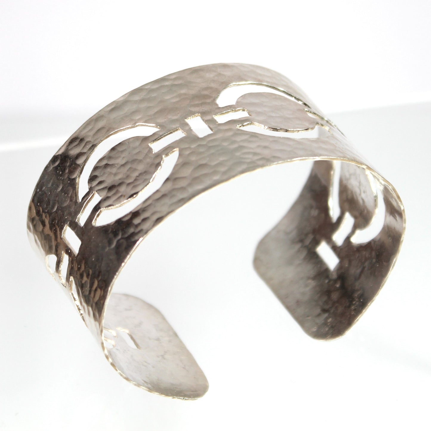 Meticulously pierced and hammered by hand from sterling silver, this handcrafted statement cuff features a stylish linked circle chain design. This wide yet comfortable cuff bracelet is versatile and adds a touch of sophistication to any ensemble, day or night.