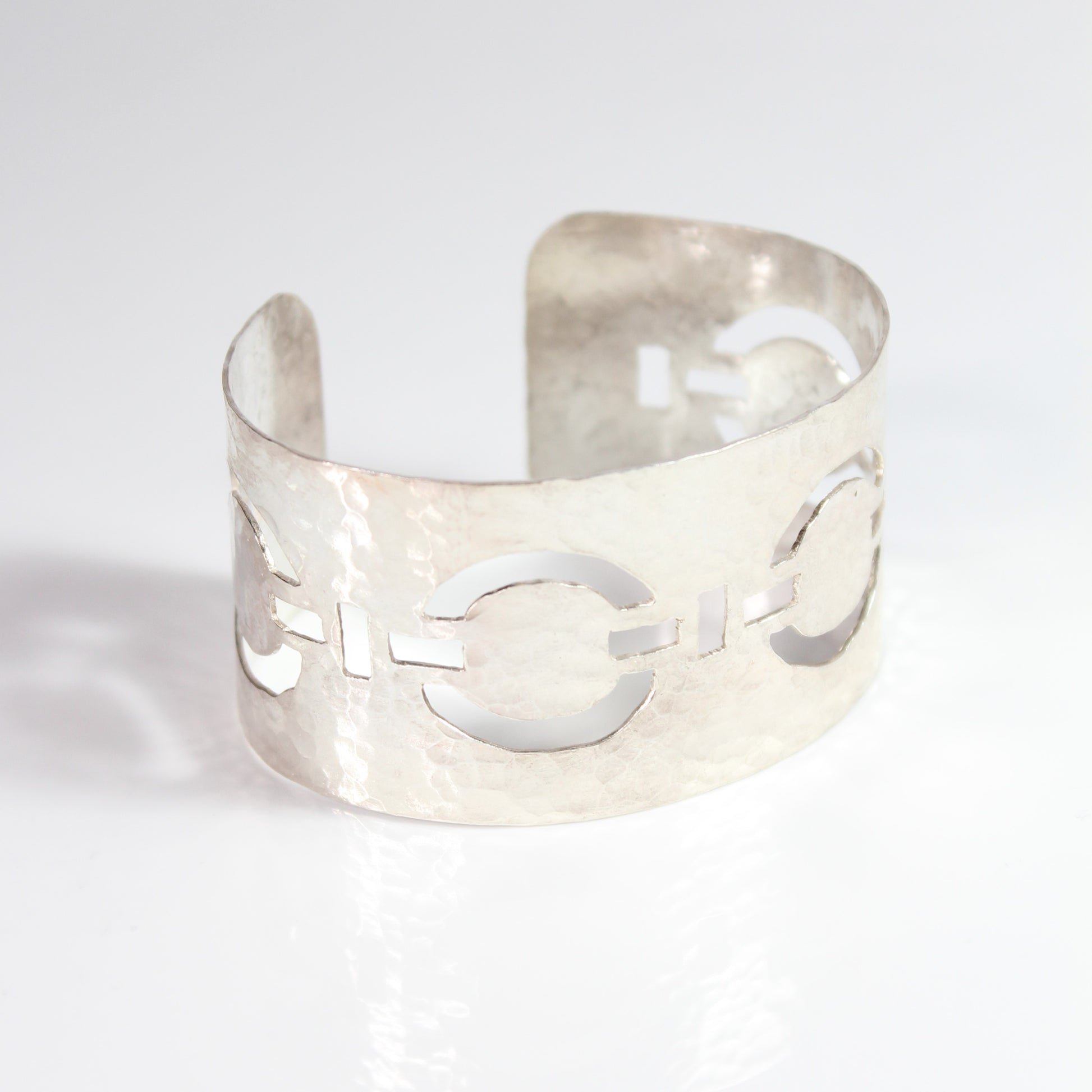 Meticulously pierced and hammered by hand from sterling silver, this handcrafted statement cuff features a stylish linked circle chain design. This wide yet comfortable cuff bracelet is versatile and adds a touch of sophistication to any ensemble, day or night.