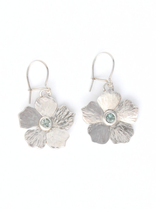Silver flower-shaped earrings with a central light blue tourmaline gemstone on a white background